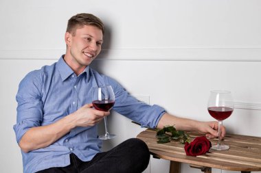 Genç ve yakışıklı bir adam kafeteryada oturmuş kız arkadaşını bekliyor.