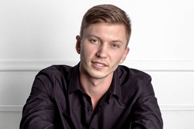 Siyah gömlekli pensive genç yakışıklı adam sandalyede oturan ve kameraya bakarak