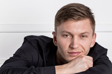 Siyah gömlekli pensive genç yakışıklı adam sandalyede oturan ve kameraya bakarak