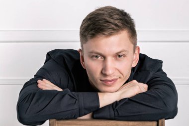 Siyah gömlekli pensive genç yakışıklı adam sandalyede oturan ve kameraya bakarak