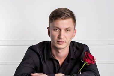 Yakışıklı adam siyah gömlek giyen bir gül tutan ve romantik tarih hazırlanıyor