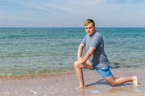 Hombre guapo haciendo ejercicio en la playa, entrenando al aire libre. Concepto de deporte y fitness —  Fotos de Stock