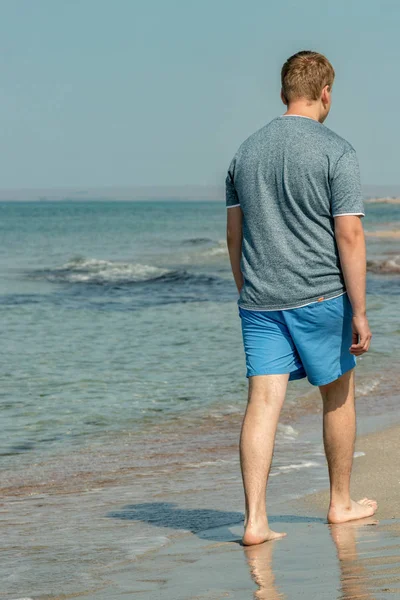 Hombre guapo caminando solo en la playa con los pies desnudos. Descanse junto a la playa . —  Fotos de Stock