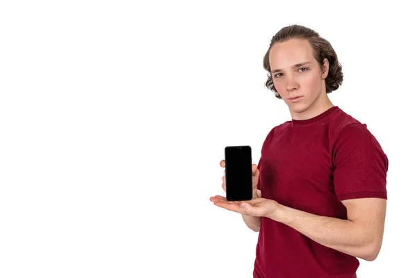 Schöner junger Mann im T-Shirt mit leerem Bildschirm-Smartphone vor weißem Hintergrund — Stockfoto