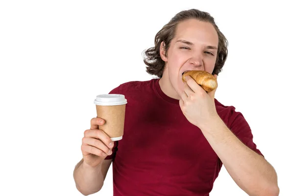 Jonge knappe man drinken koffie en eten croissant. Frans ontbijt en 's ochtends koffie. Geïsoleerd — Stockfoto