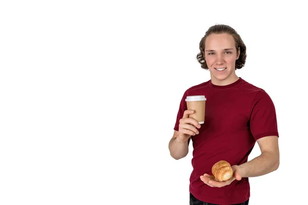 Genç yakışıklı adam kahve içer ve kruvasandan yiyor. Fransız kahvaltısı ve sabah kahvesi. Izole — Stok fotoğraf