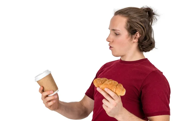 Jovem bonitão bebe café e come croissant. Café da manhã francês e café da manhã. Isolados — Fotografia de Stock