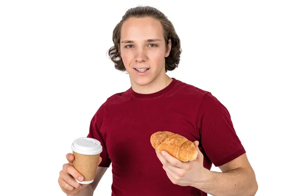 Fiatal jóképű ember iszik kávét és étkezési croissant. Francia reggeli és reggeli kávé. Elszigetelt — Stock Fotó