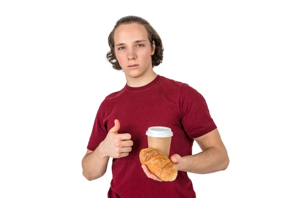 Jovem bonitão bebe café e come croissant. Café da manhã francês e café da manhã. Isolados — Fotografia de Stock