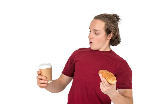 Giovane bell'uomo bere caffè e mangiare croissant. Colazione francese e caffè del mattino. Isolato — Foto Stock