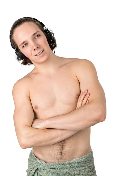 Pohledný nahý mladý muž v ručníku, který poslouchá hudbu ve sluchátkách na bílém pozadí izolovanému — Stock fotografie