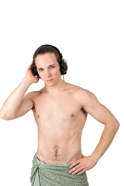 Guapo joven desnudo en toalla escuchando música en auriculares sobre fondo blanco aislado —  Fotos de Stock