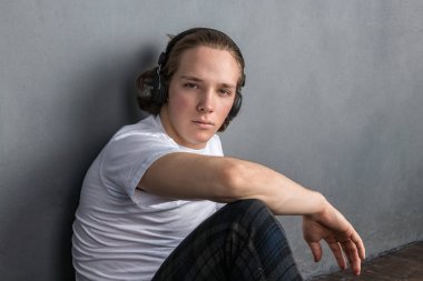 Oturma odasında yerde oturan yakışıklı genç adam, kafasına kulaklık sahip ve müzik dinleme