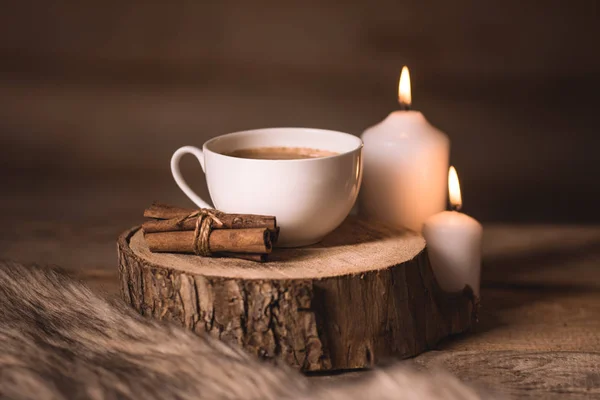 White cup of coffee, candles, cinnamon and fur — Stock Photo, Image