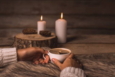 elinde kahvesiyle beyaz fincan bir kız, kürk, koni ve mumlar 