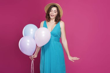 güzel esmer bir mavi elbise ve hasır şapka balon tutar 