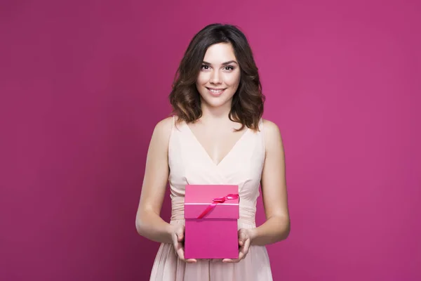 Morena sonriente en un vestido sosteniendo una caja de regalo en sus manos — Foto de Stock