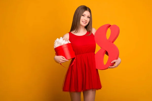Hermosa rubia en un vestido rojo con un regalo y el número ocho en las manos — Foto de Stock