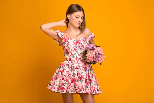 Hermosa rubia con un ramo de flores en un vestido — Foto de Stock