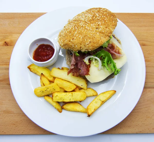 Hamburger with lettuce and cheese, fries and ketchup, on wooden table