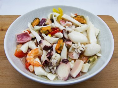 Tahta masada beyaz tabak karışık Akdeniz ürünleri salatası.