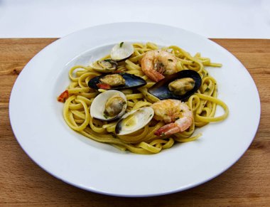 Linguine allo scoglio, ahşap masada deniz ürünleri ile İtalyan makarna çanak