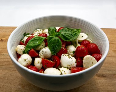 Mozzarella ve domates beyaz kasede. Ahşap masa, beyaz arka plan 