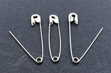 Güvenlik iğnesi, açık ve kapalı, karanlık arka planda izole edilmiş.