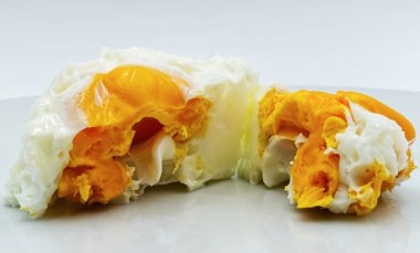 Beyaz bir tabakta haşlanmış yumurta, beyaz arka planda izole edilmiş.