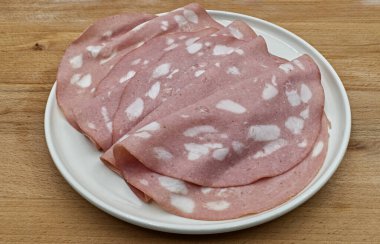 Tahta masada beyaz bir tabakta sosisli İtalyan Mortadella dilimleri. 