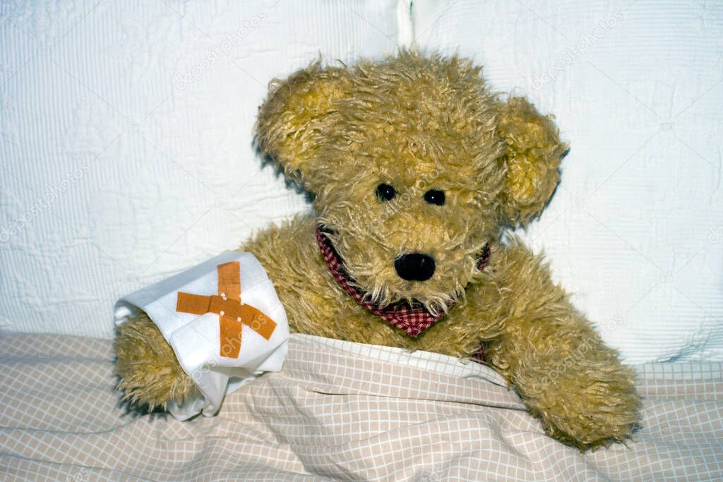 Teddy lying sick in bed .