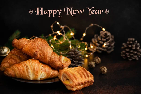 Christmas or New Year pastries, Chocolate and Apple Croissants. Christmas Eve mood. Winter holidays concept with text - Merry Christmas and Happy New Year. Dark background