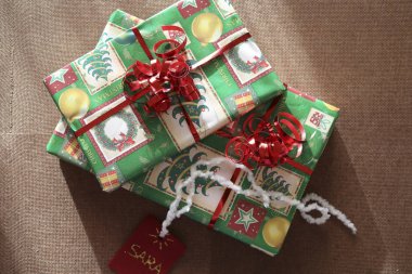 Close-up iki hediye paketleri ile Sara isim kartı, yeşil kart ve kırmızı yay, kahverengi zemin ile üstten görünüm