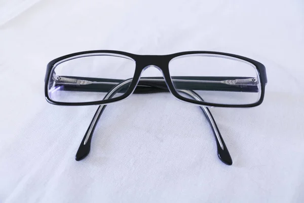 Close-up of a pair of black eyeglasses, white background, everyday objects