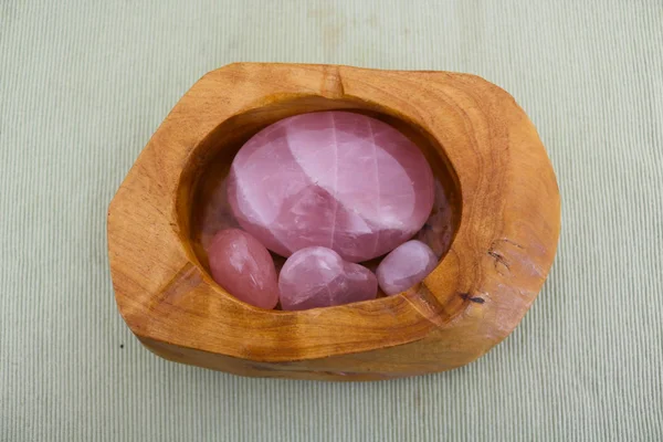 Rose quartz, pink precious stones inside a wooden container viewed from above, collectors items