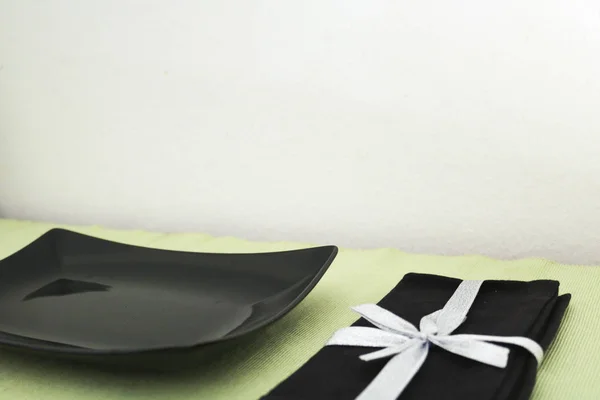 Schwarzer Quadratischer Teller Und Serviette Auf Grünem Tischtuch — Stockfoto