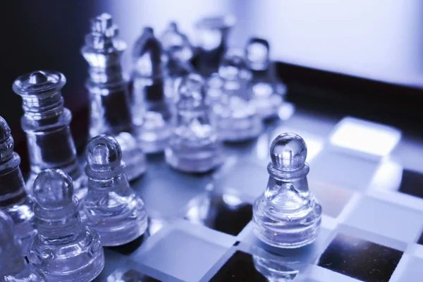 Detail of a chessboard and glass pawns, games of society and logic