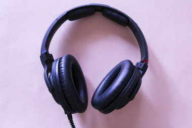 Yukarıdan görüntülenen pembe arka plan da müzik için kulaklıklar, müzikal nesneler
