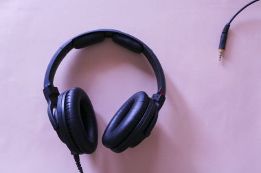 Yukarıdan görüntülenen pembe arka plan da müzik için kulaklıklar, müzikal nesneler