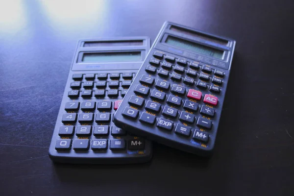 Two calculators on a black background, office objects