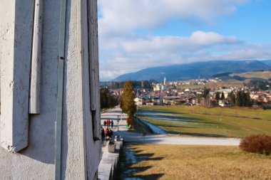 Beautiful panoramic view of the meadows, the red colored trees and the Asiago plateau from the military shrine of Asiago, travel and landscapes in Veneto clipart