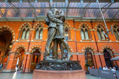 London, UK - May 14 2018: The Meeting Place, 9-metre bronze statue revealed in 2007, stands at the south end of the upper level of St Pancras railway station by British artist Paul Day clipart