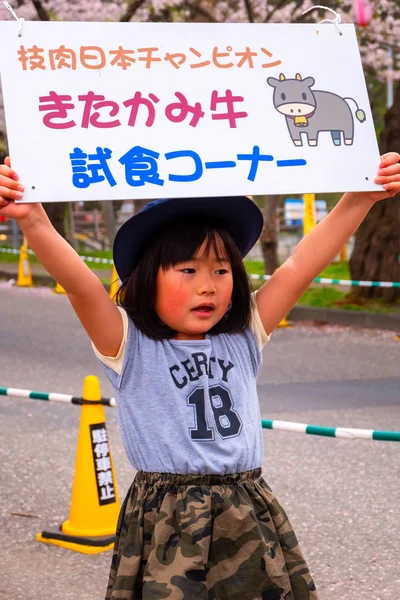日本岩手县 2018年4月22日 在北上天下公园盛开樱花节期间 不明身份的日本年轻女孩举着招牌 为游客出售北谷牛肉 — 图库照片