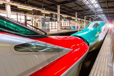 Iwate , Japan - April 22 2018: Japanese Shinkansen high speed train Hayabusa (green) and Komachi (red) join together at Kitakami Station travel up north east of Japan from Tokyo clipart