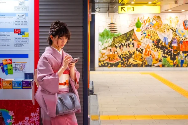 Japonská žena v tradičních šatech v kimono posouvá smartphone do stanice metra — Stock fotografie