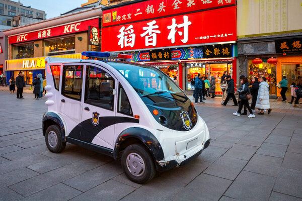 Beijing, China - Jan 9 2020: A small EV police  patrol car observes and guards people along the shopping street of Wangfujing