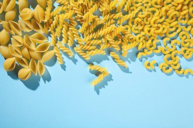 Makarna mavi bir arka plan üzerine farklı türleri. Trend renkler. Doğa Tarım makarna. Düdük, conchiglie ve üzerinde mavi arka plan izole maccheroni. Kopya alanı metin logo veya marka için. 