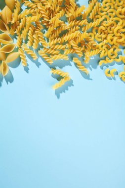 Makarna mavi bir arka plan üzerine farklı türleri. Trend renkler. Doğa Tarım makarna. Düdük, conchiglie ve üzerinde mavi arka plan izole maccheroni. Kopya alanı metin logo veya marka için. 