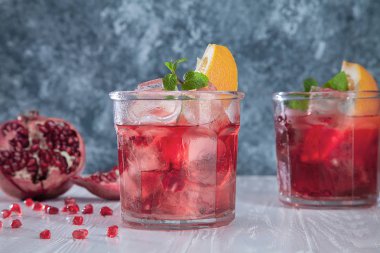 Taze nar kokteyl ingridients ile nane, turuncu ve mavi soğuk beton arka plan ile. Kırmızı kokteyl kapatın. Kopya alanı metin, logo veya marka için.