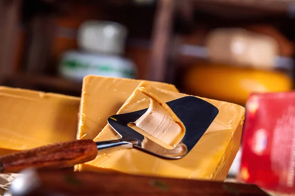 Block of Traditional Norwegian sweet brown cheese and cheese cutter. Gudbrandsdalsost. Close up view. Copy space for text, logo or brand. Delicious cheese on wooden table in shop.